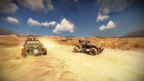 Two cars are speeding down a sandy road. Both heavily modified and covered in extra armor and dirt. Prairie with patches of small vegetation stretches far into the bright blue sky with fluffy white clouds.