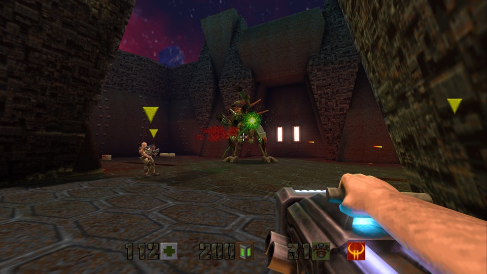 First-person view of a character firing a BFG10K at the final boss, Makron, who controls an exoskeleton that resembles a goat-like demon. There are on-screen indicators of at least three other players, one of whom is a human male soldier, another is a cyborg, and the third is obscured by a pillar.