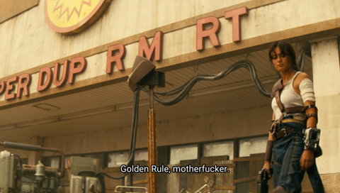 Lucy, one of the protagonists, in an iconic Fallout look: blue jumpsuit pulled down to look like pants, white tank top, a leather shoulder pad, Pip-Boy on her wrist, and a handgun in her hand. She is standing in front of a ruined Super-Duper Mart. The subtitle reads “Golder Rule, motherfucker.”