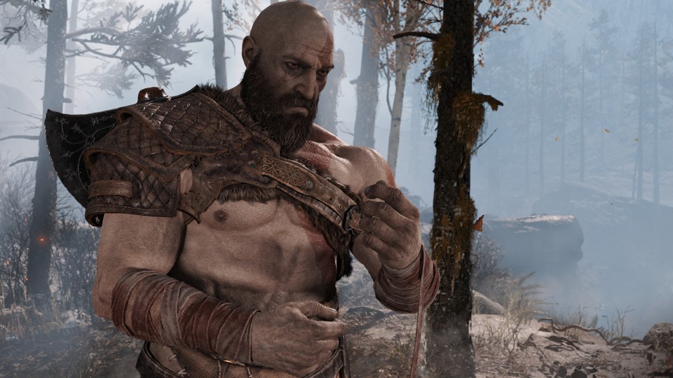 Kratos is a big, buff dude with pale skin, a shaved head, a bushy beard with some gray hairs in it, and scars over his right eye and on his stomach. He has a red line on the left side of his head and chest. He is almost topless with a leather pauldron over his right shoulder and long strips of cloth covering his forearms. He starts to unwrap one of the straps with a serious and somewhat sad look on his face.